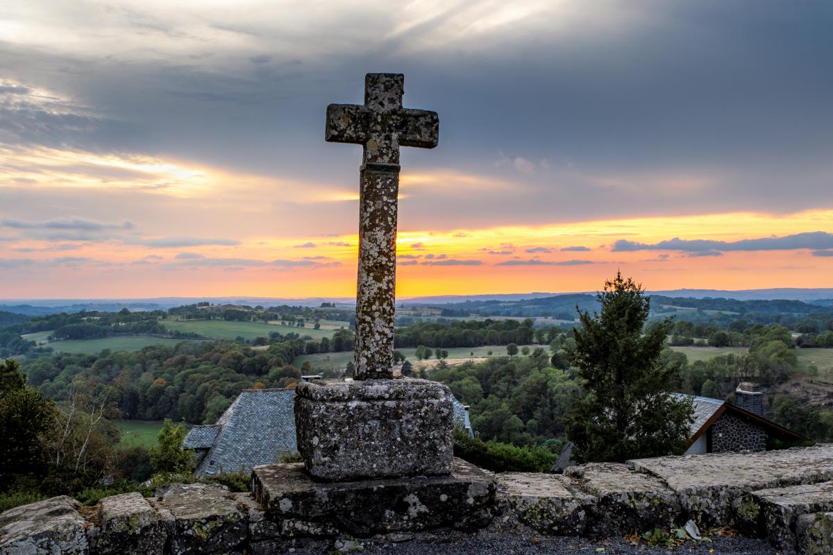 Croix devant un paysage d'Aubrac au coucher du soleil